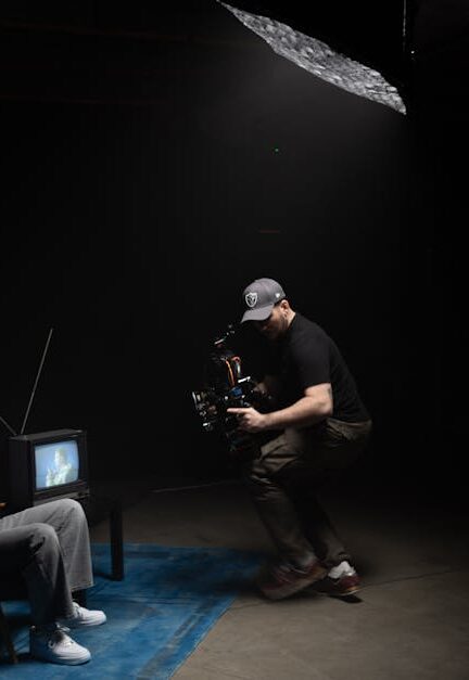 A photographer captures a scene with a man sitting next to an old TV in a dimly lit studio.