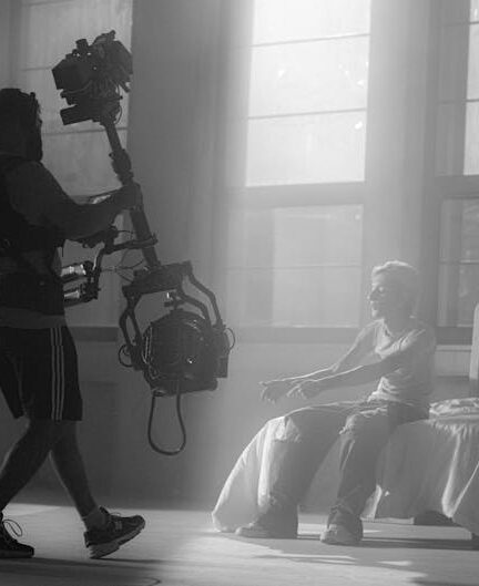 Filmmakers using camera rig for artistic shot in moody setting with dramatic lighting.