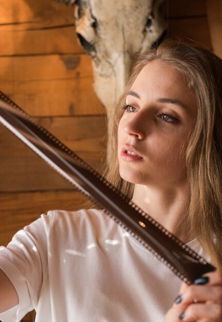 A young woman intently examines a strip of photographic film, surrounded by rustic indoor decor.