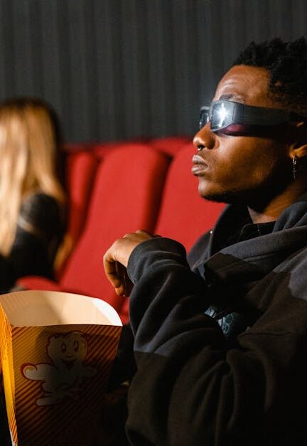 A group of adults in a cinema wearing 3D glasses watching a movie and eating popcorn.