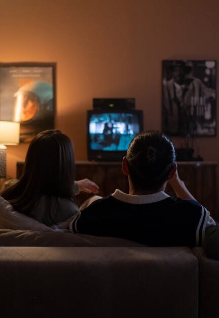 Three people enjoying a relaxed movie night at home, sitting on a couch in a cozy living room.