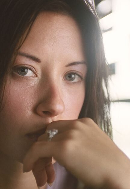 A vintage-style portrait capturing a woman's thoughtful expression in a serene indoor setting.
