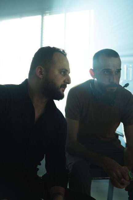 Film crew members collaborating in a Baghdad studio with dramatic lighting.
