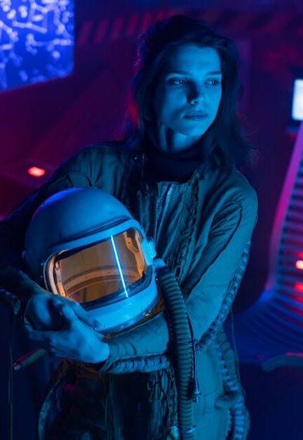 A woman in a futuristic setting holding a spacesuit helmet, illuminated by neon lights.