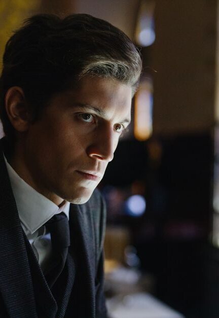 Close-up of a thoughtful man in a black suit in an elegant indoor setting.